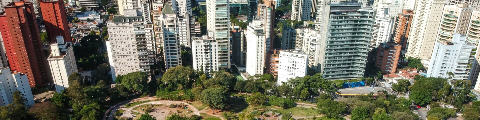 An aerial view of a park with pathways, open grassy areas, and surrounding tall buildings.