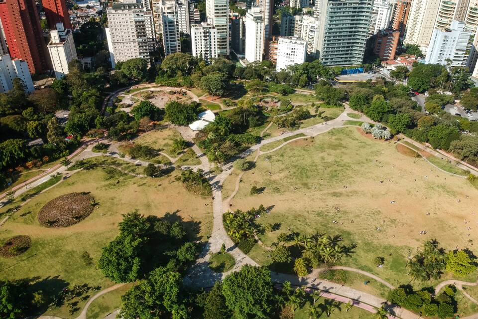 Vista aérea de un parque con senderos, zonas verdes abiertas y altos edificios circundantes.