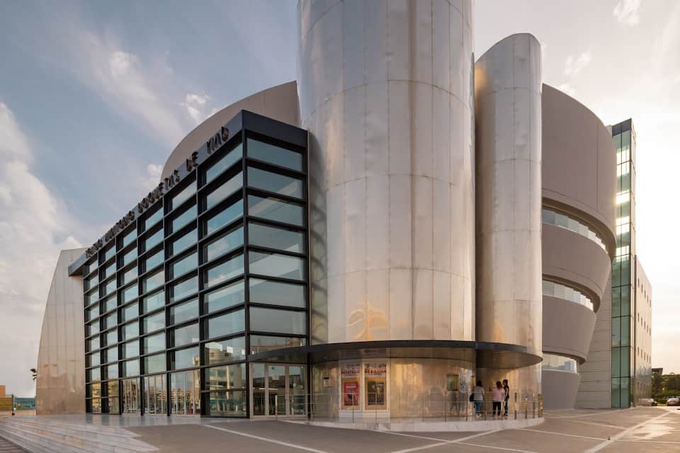 A modern building with a curved facade and large cylindrical structures.