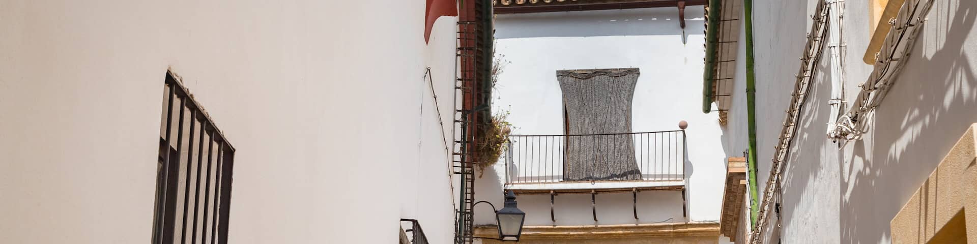 Una calle estrecha con edificios blancos, una puerta de madera y un balcón con techo de tejas.