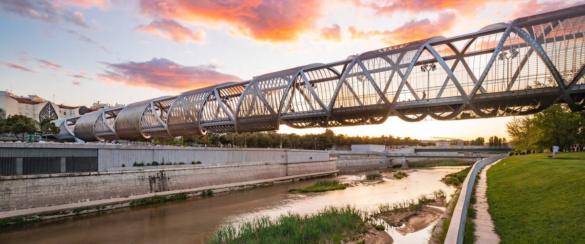 Puente Monumental Parque de Arganzuela featuring a sunset, a river or creek and a bridge
