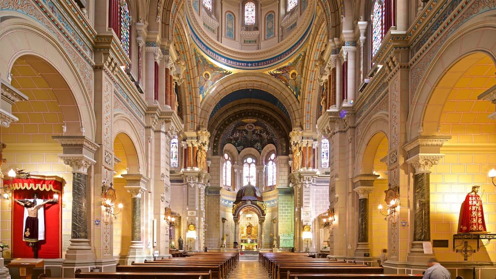 An ornate church interior with high ceilings, stained glass windows, and a central altar.