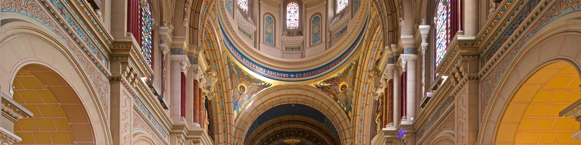 An ornate church interior with high ceilings, stained glass windows, and a central altar.