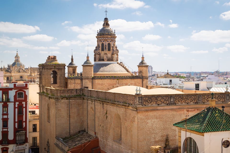 A historic cathedral with a prominent dome and bell towers, surrounded by urban buildings.