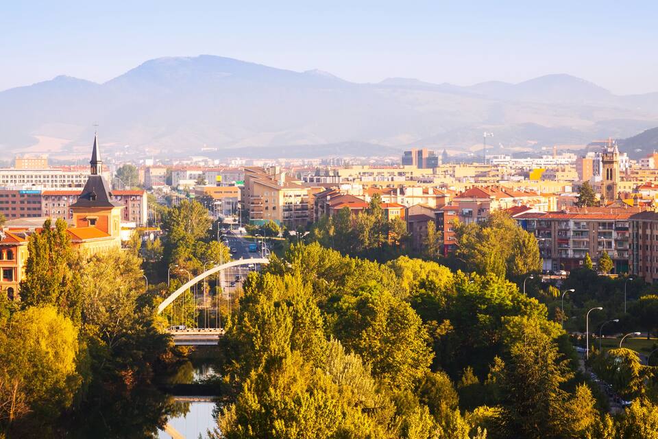 A cityscape with a prominent church, a river, and mountains in the background.