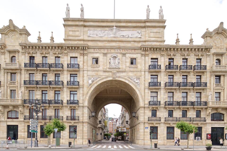 A grand archway with the inscription "Banco de Santander" above it, flanked by ornate buildings with balconies and statues.