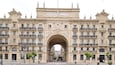 A grand archway with the inscription "Banco de Santander" above it, flanked by ornate buildings with balconies and statues.