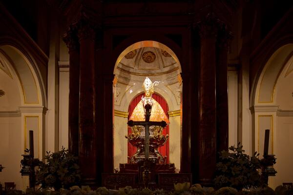 An ornate religious altar with a central statue, flanked by columns and floral arrangements.