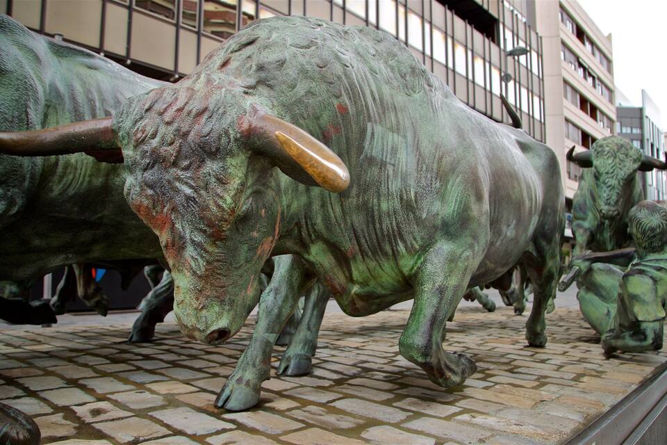 A bronze bull statue on a cobblestone street.