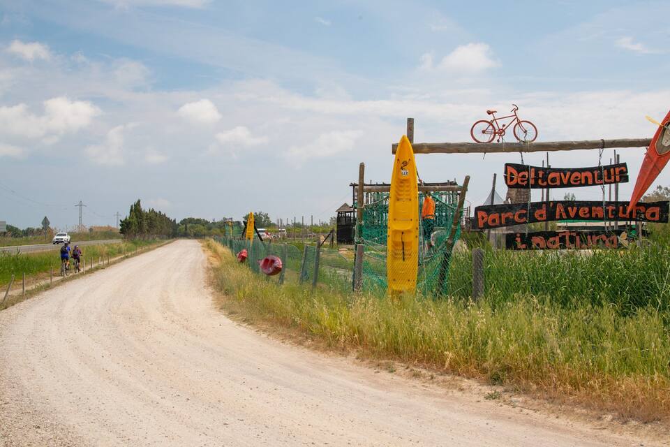 A dirt road with a sign for 'Deltaventur Parc d'Aventura'.