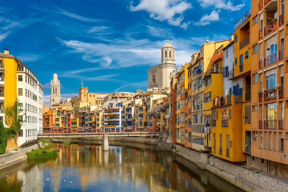 A canal with colorful buildings and a tower in the background.