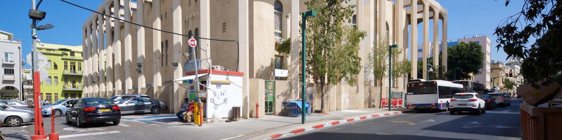 Un edificio moderno con recortes circulares y una parada de autobús cerca.