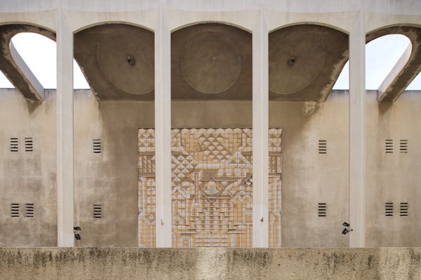 A building facade with three arches and a central decorative panel.