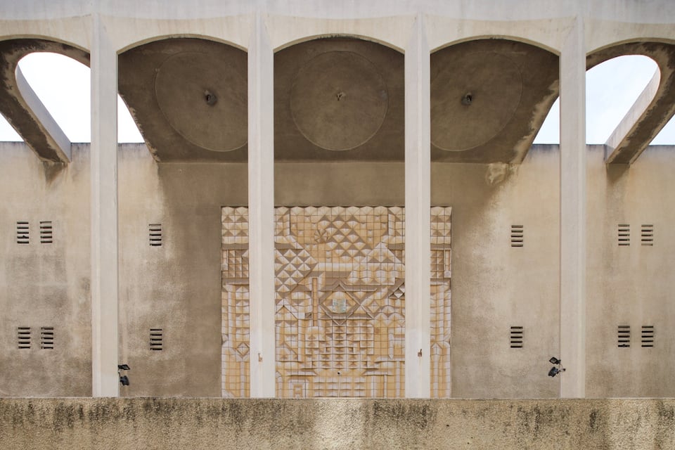A building facade with three arches and a central decorative panel.