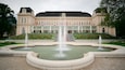 A large building with a fountain in front.