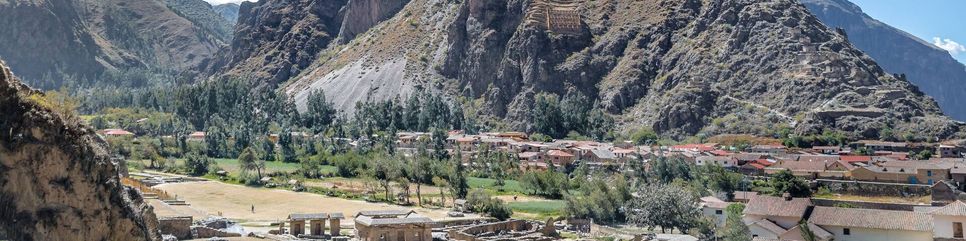 A mountainous landscape with a village nestled at its base, featuring terraced fields and traditional buildings.