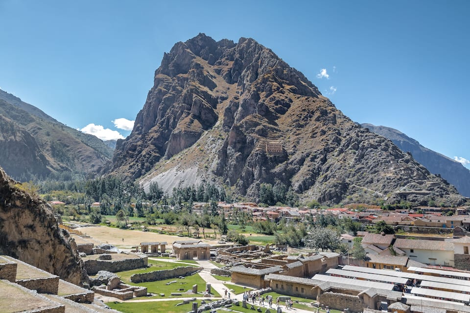 A mountainous landscape with a village nestled at its base, featuring terraced fields and traditional buildings.
