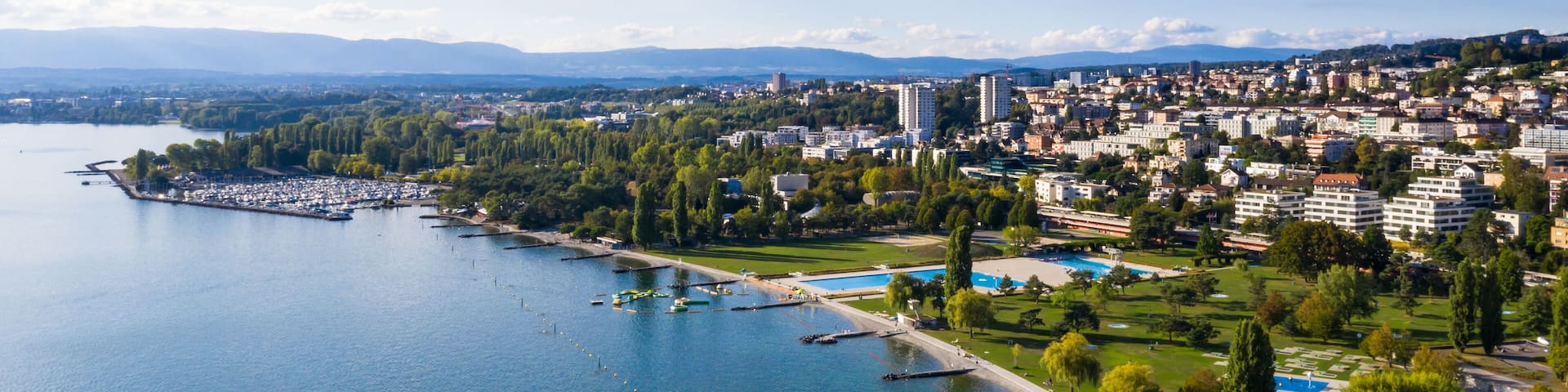 Une rivière avec des bateaux, un parc et un paysage urbain avec des bâtiments.