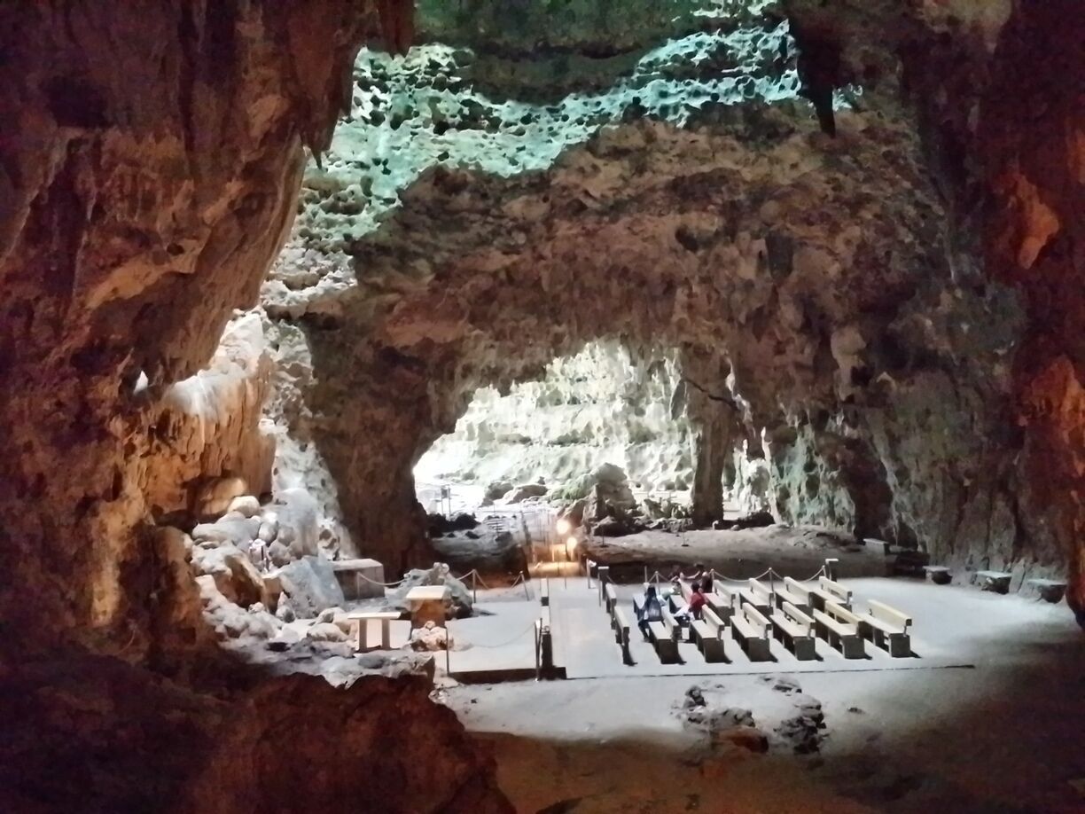 A cave with a large opening, a wooden platform, and a seating area.