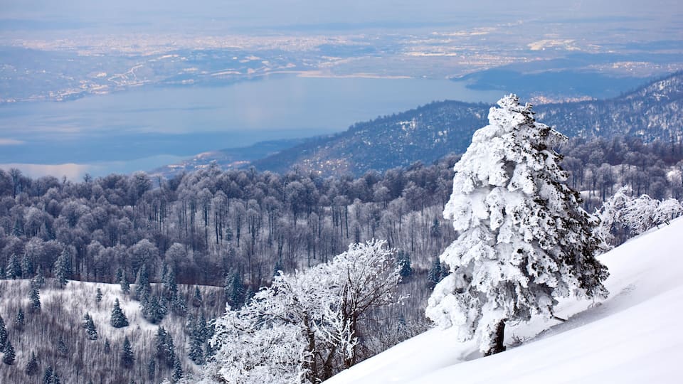 A snow-covered mountain landscape with a lake in the distance.