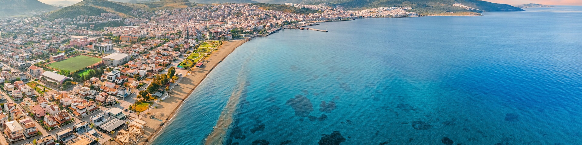Stunning aerial view of Dikili coastline, bathed in the warm glow of sunset, showcasing the beautiful turquoise waters of the Aegean Sea