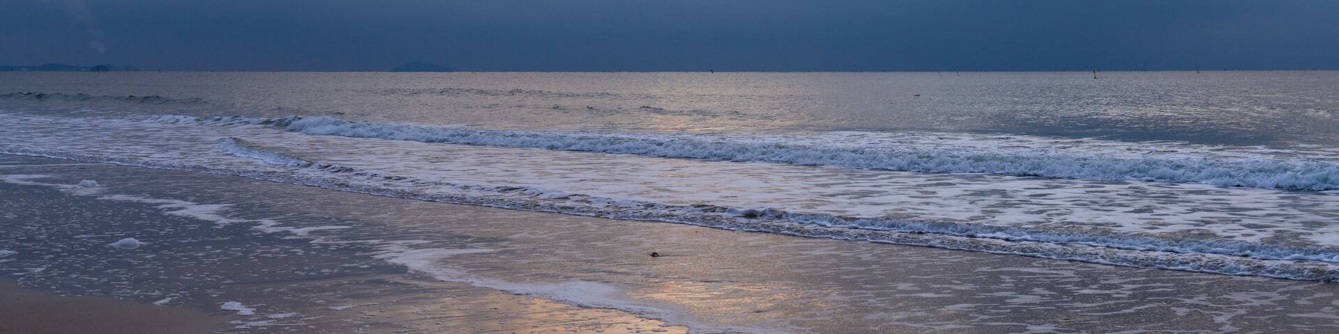 tranquil seascape with surfs on the beach during sunset