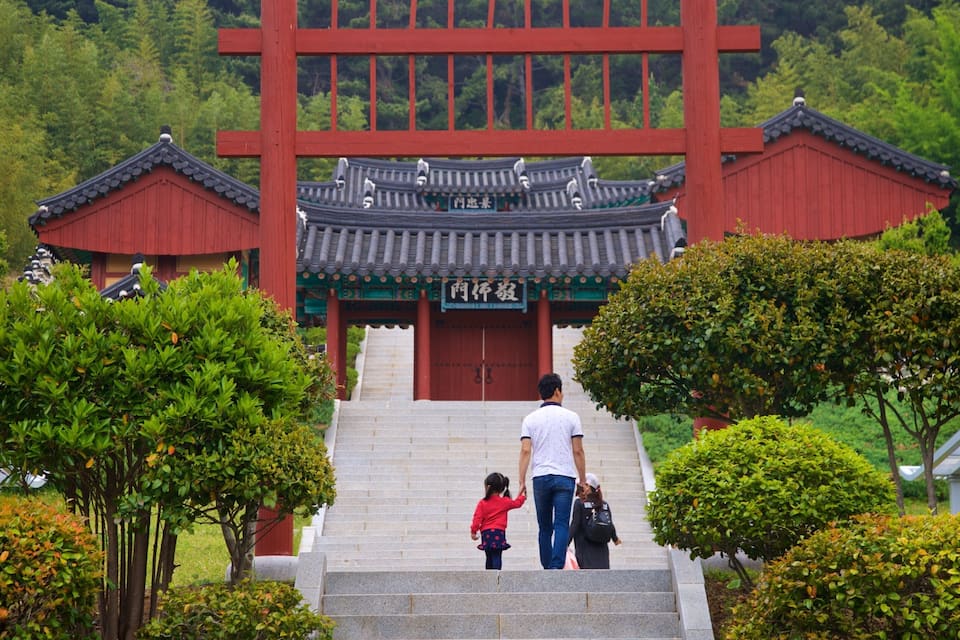 A traditional Korean gate with a red roof and a sign with Chinese characters.