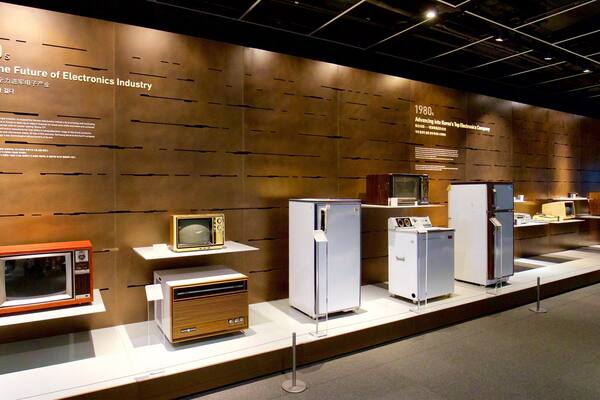 A museum exhibit of vintage electronics from the 1970s and 1980s, including TVs, microwaves, and refrigerators.