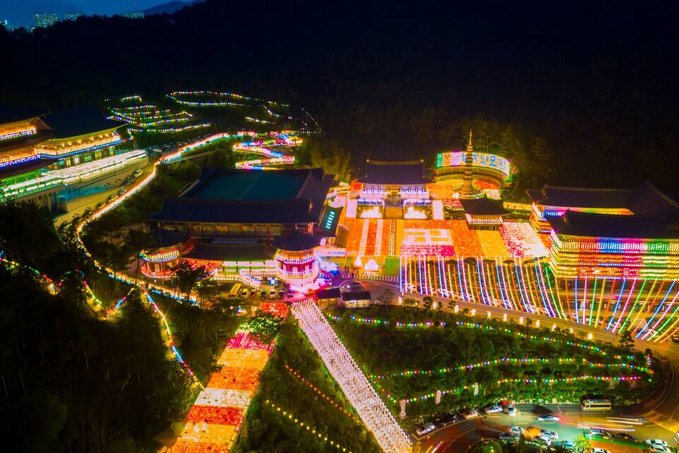 Un complejo arquitectónico tradicional chino, muy iluminado, con elaboradas exhibiciones de luces, senderos serpenteantes y una pagoda central.