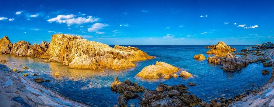 A coastal landscape with rocky formations and clear blue waters.
