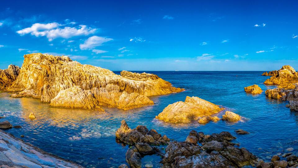 A coastal landscape with rocky formations and clear blue waters.