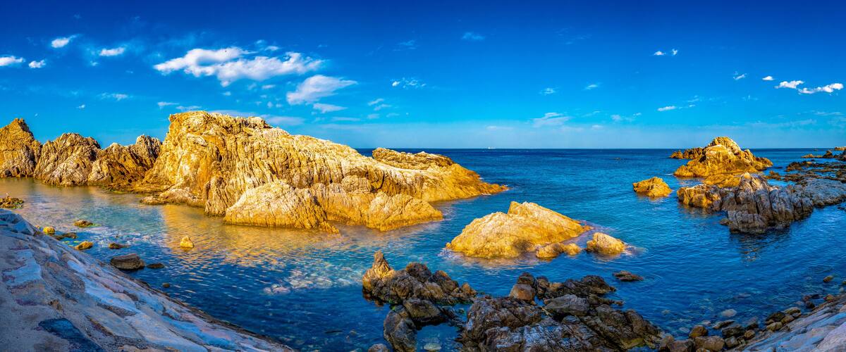 A coastal landscape with rocky formations and clear blue waters.