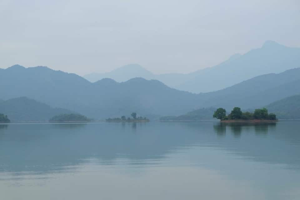 A calm lake with several small islands and distant mountains.