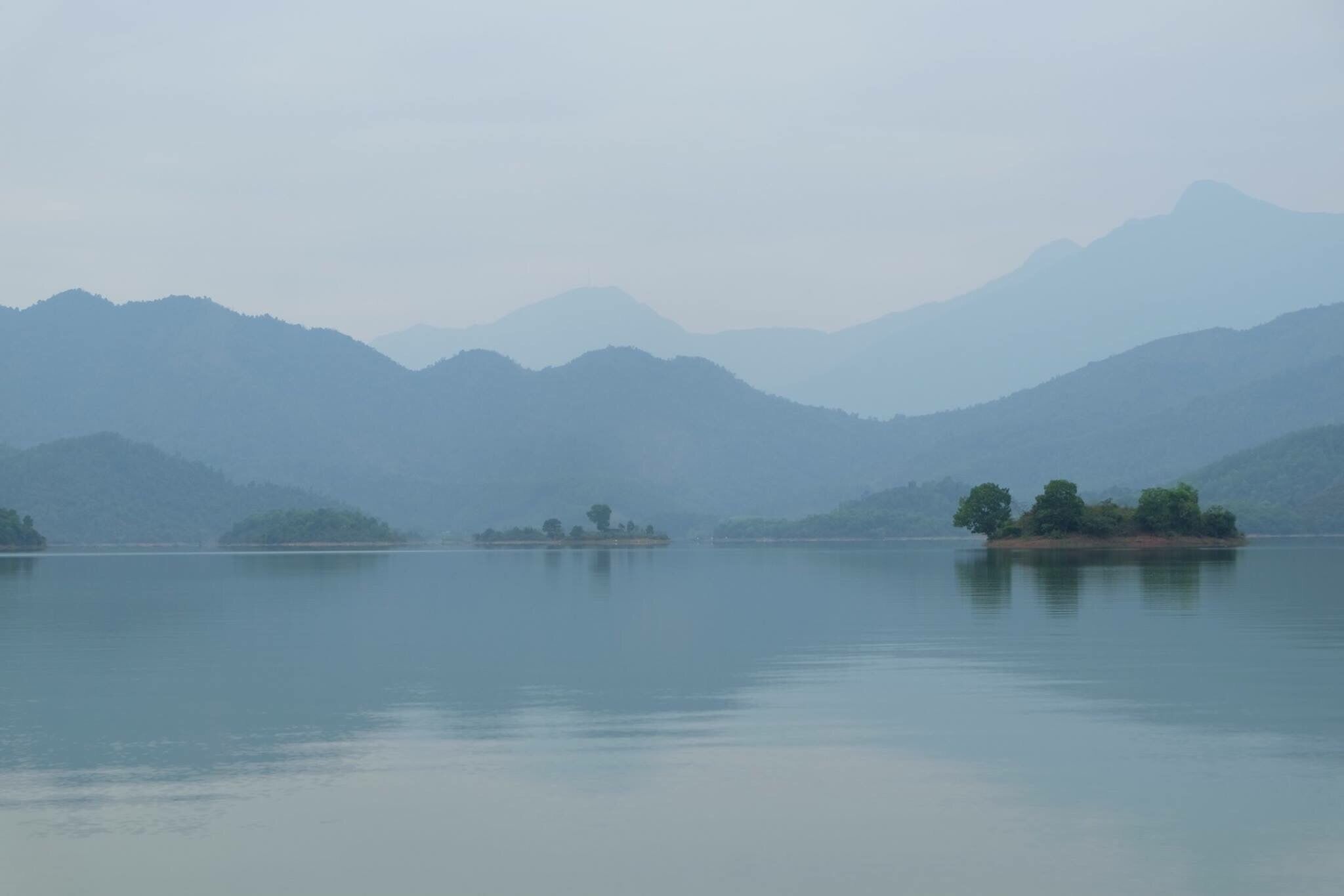 A calm lake with several small islands and distant mountains.