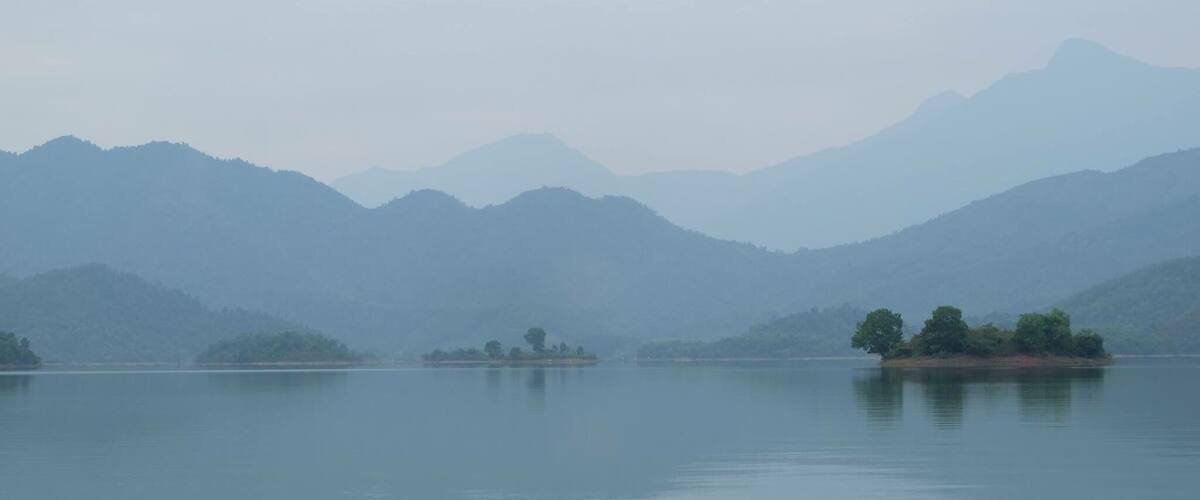 A calm lake with several small islands and distant mountains.