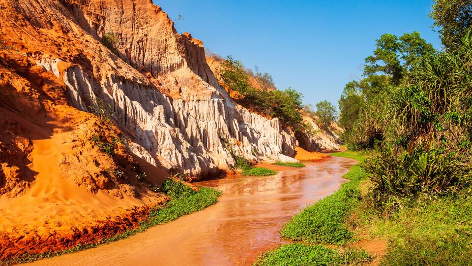 A river flowing through a canyon with red and white rock formations.