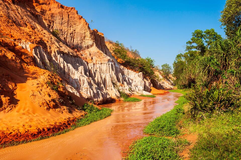 A river flowing through a canyon with red and white rock formations.
