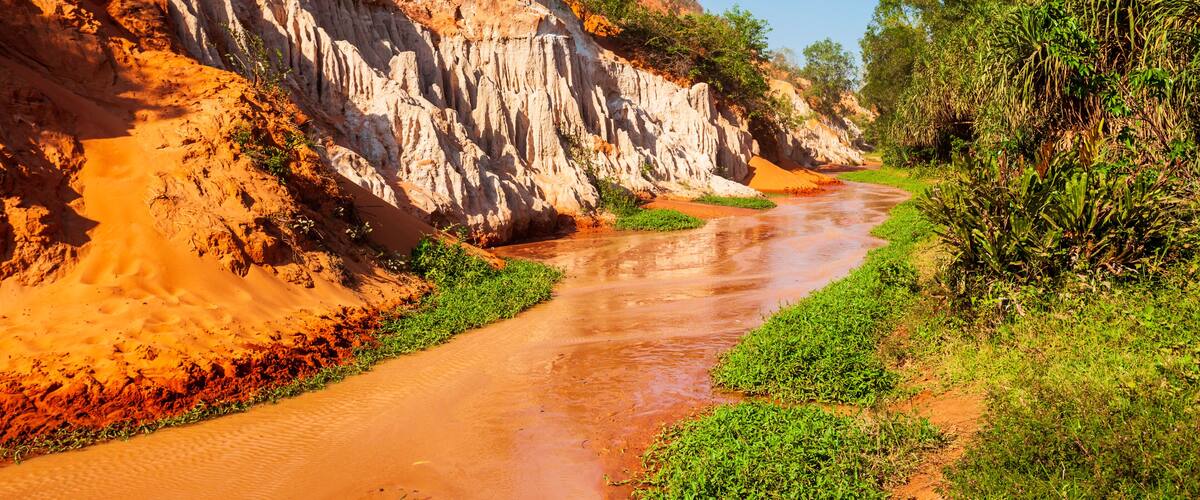 A river flowing through a canyon with red and white rock formations.