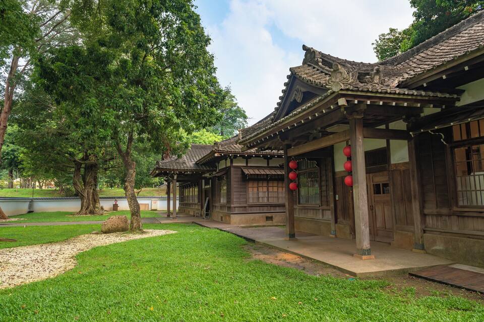 A traditional wooden building with tiled roofs and red lanterns.