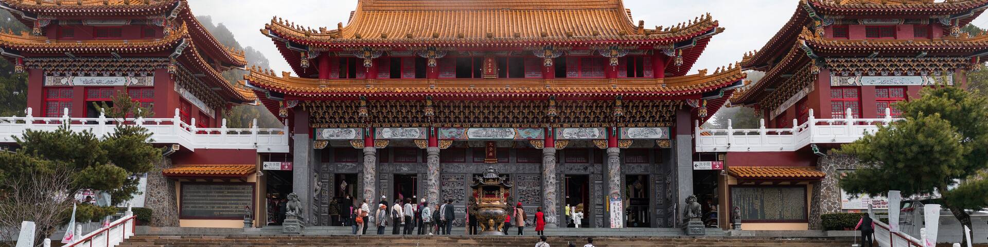 A traditional Chinese building with ornate red and gold roofs, multiple tiers, and a large staircase leading up to the entrance.