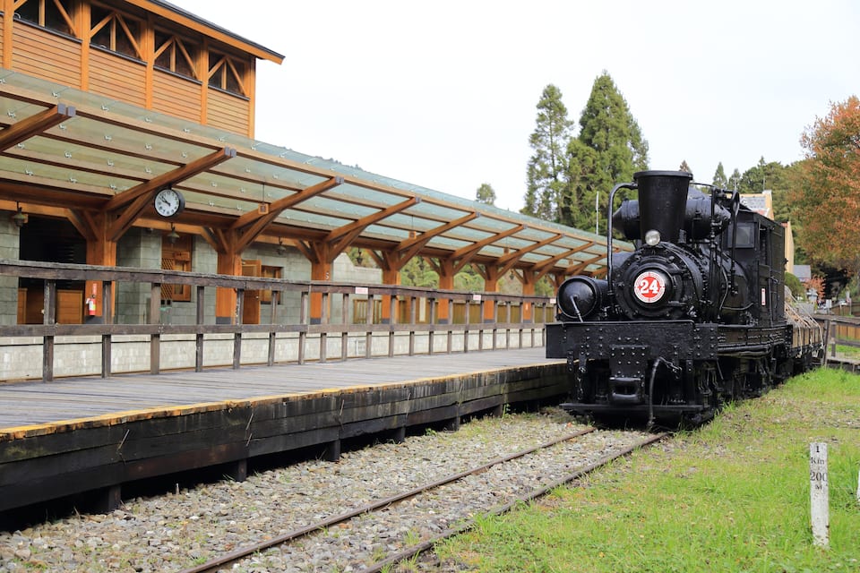 Una locomotora de vapor negra a l'andana d'una estació de tren de fusta.