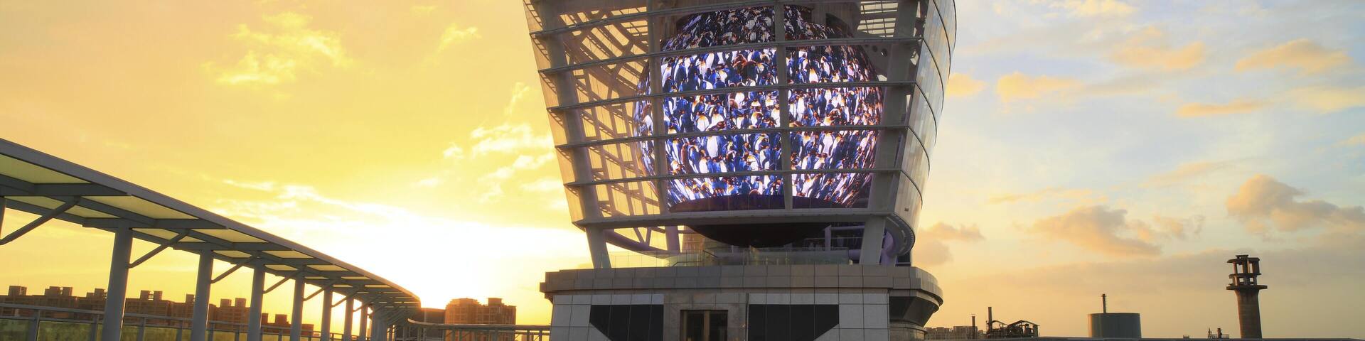 Una estructura arquitectónica moderna con fachada de vidrio que refleja el atardecer.