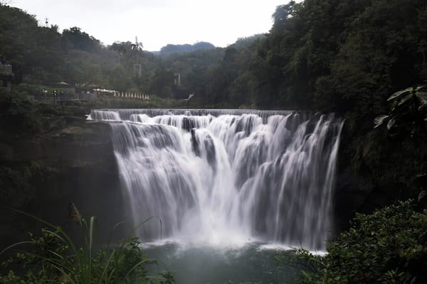 A multi-tiered waterfall surrounded by dense forest.