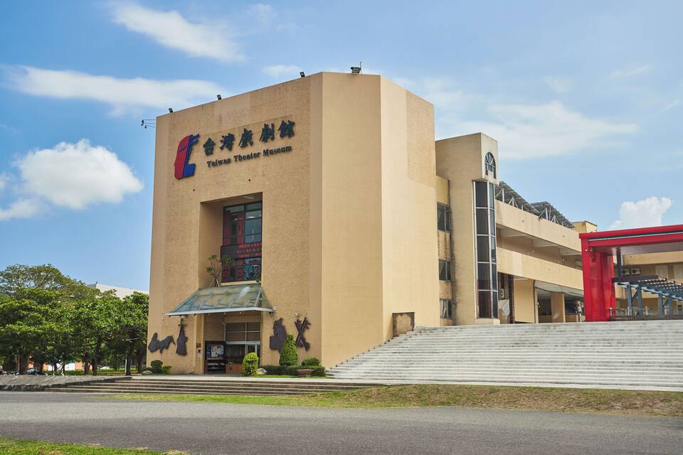 Museu do Teatro de Taiwan, com um céu azul claro e uma estrutura vermelha ao fundo.
