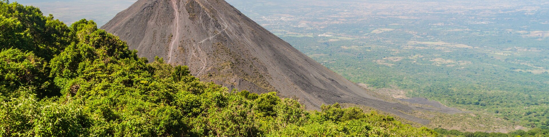 Una montaña con un pico prominente, rodeada de un denso bosque verde.