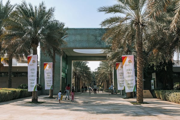 Une promenade piétonne bordée de palmiers et de banderoles faisant la publicité du marché « The Park Market ».