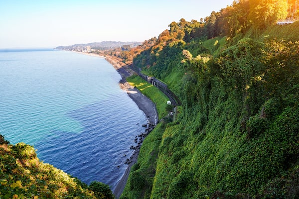 Beautiful, bewitching view of the blue sea, green cape and the railway from the botanical garden in Batumi Georgia in clear sunny day