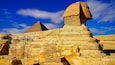 A grand view of the Great Sphinx of Giza with scaffolding for restoration work on a bright hot day on the Giza plateau with the Pyramid of Khufu in the background