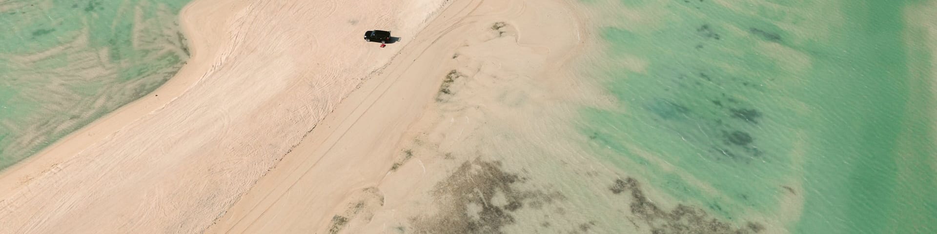 An aerial view of a coastal area with sandy beaches and clear turquoise waters.