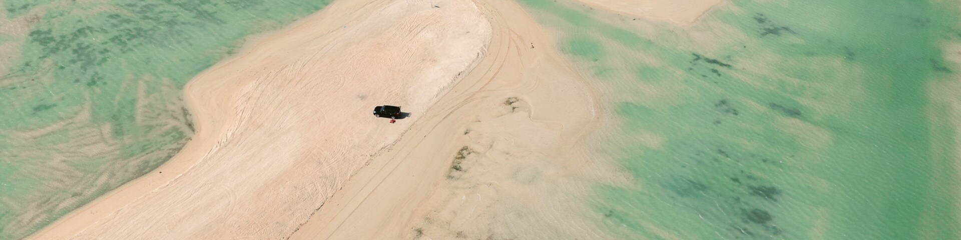 Vista aérea de una zona costera con playas de arena y aguas turquesas cristalinas.